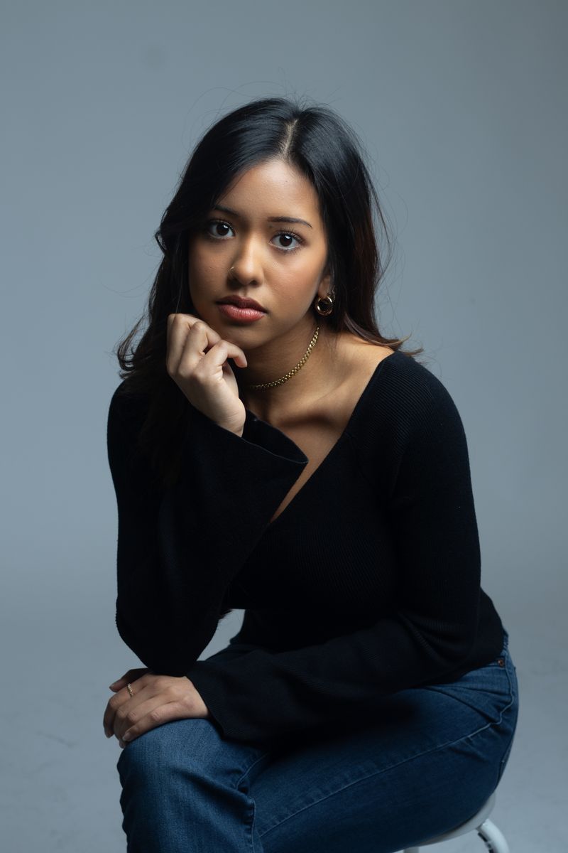Woman seated, studio portrait on blue-grey